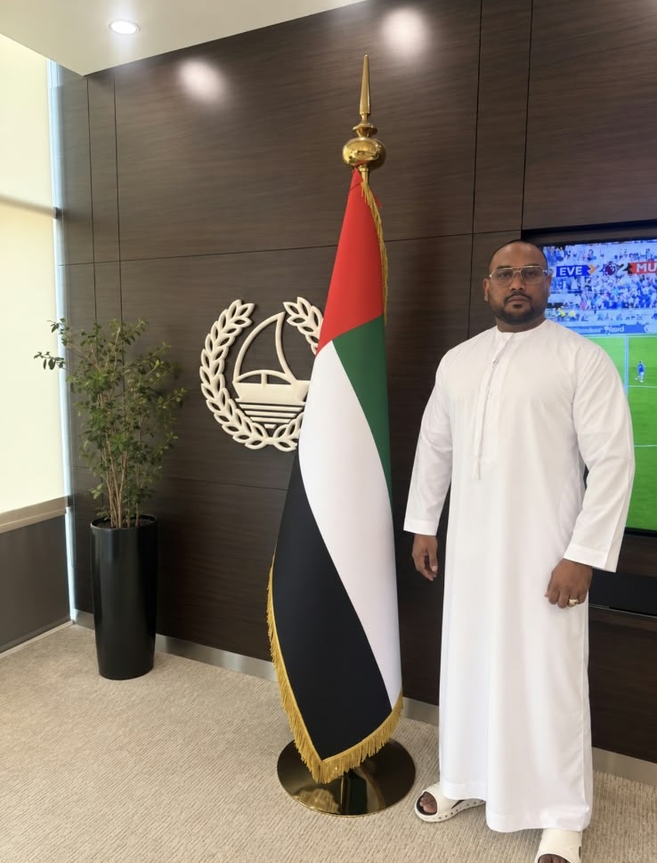 Mohamed Sameer Ismail beside the UAE flag during a visit to Dubai Police